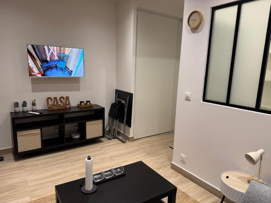 un salon avec une table et une télévision au mur dans l'établissement studio porte de paris-Saint-Ouen - Emile Zola, à Saint-Ouen