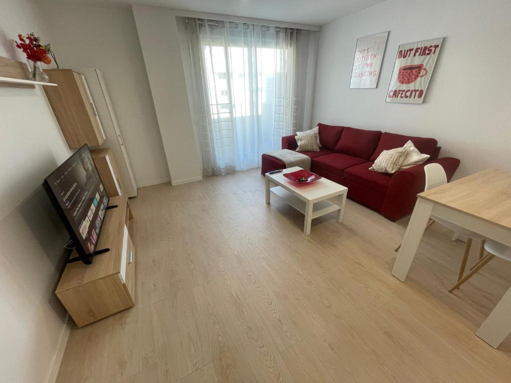a living room with a red couch and a table at M3 Rivas Futura Apartment in Rivas-Vaciamadrid