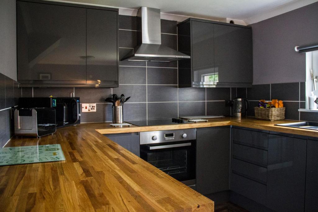 a kitchen with black cabinets and a wooden counter top at Home Farm Apartments in Portree