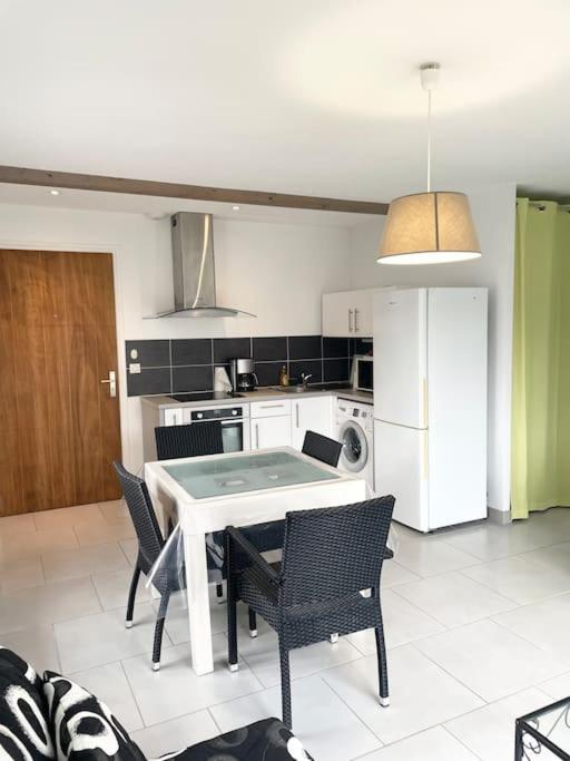 une cuisine avec une table, des chaises et un réfrigérateur dans l'établissement Appartement T2 lumineux, très bien équipé, proche centre-ville, à Salies-de-Béarn