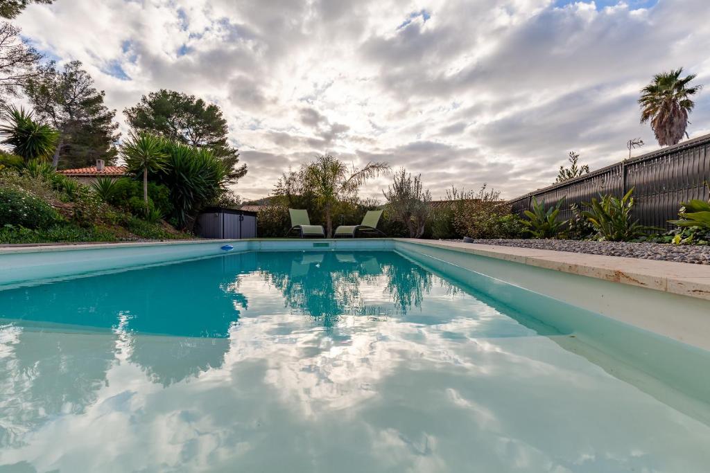 ein Pool mit Stühlen und wolkiger Himmel in der Unterkunft Bas de Villa Piscine 150m de la mer in Saint-Cyr-sur-Mer