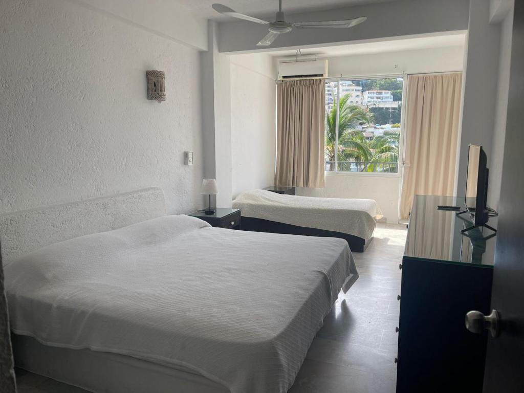 Una habitación de hotel con dos camas y una ventana. en Exclusiva y privada Villa en Marina Las Brisas, en Acapulco