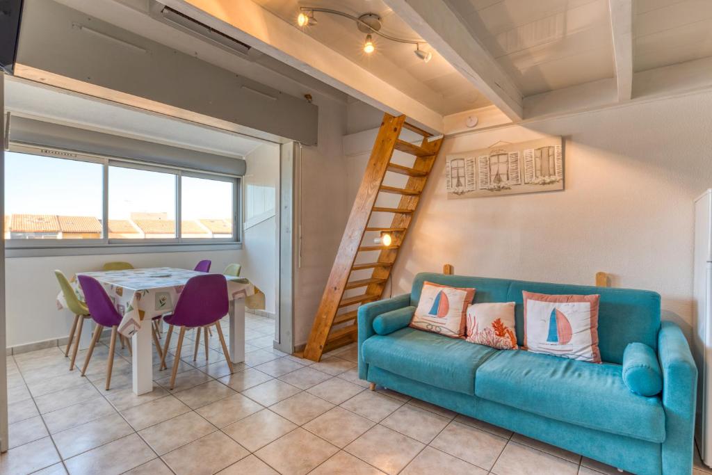 un salon avec un canapé bleu et une table dans l'établissement Appartement - La Conque, au Cap d'Agde