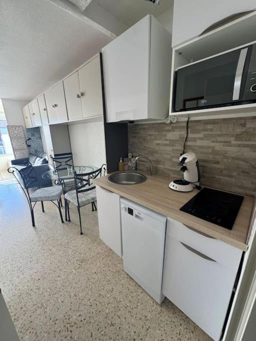 une cuisine avec un évier et une table avec des chaises dans l'établissement Appartement - Cap d'Agde, au Cap d'Agde