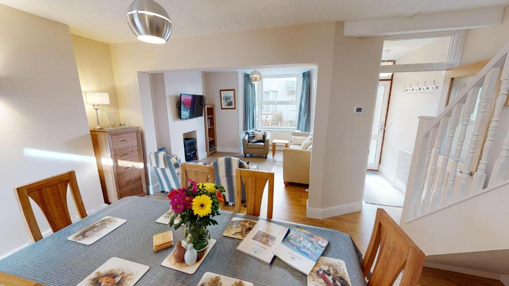 ein Esszimmer mit einem Tisch mit einer Vase mit Blumen in der Unterkunft Holmdean Cottage in Sidmouth