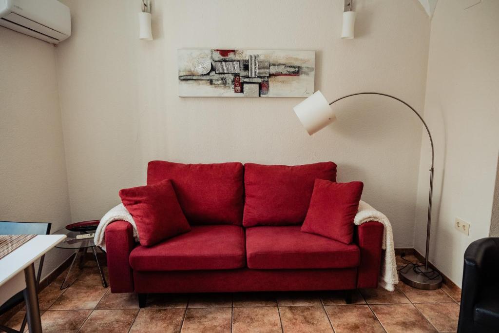 a red couch in a living room with a lamp at Apartamento Las Avutardas 1 in Cáceres