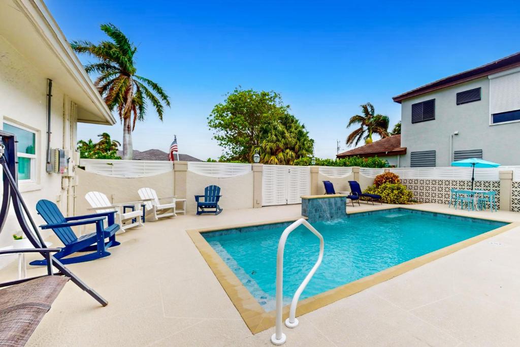 a swimming pool on a patio with chairs and a house at Lamplighter Cove in Marco Island