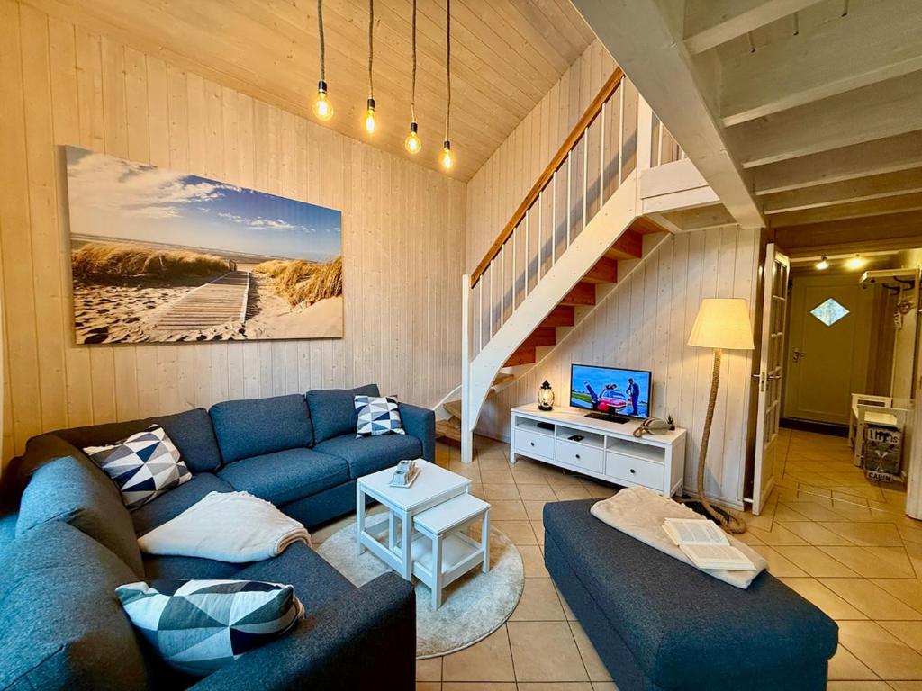 a living room with a blue couch and a staircase at Meeresblume - Baabe in Baabe
