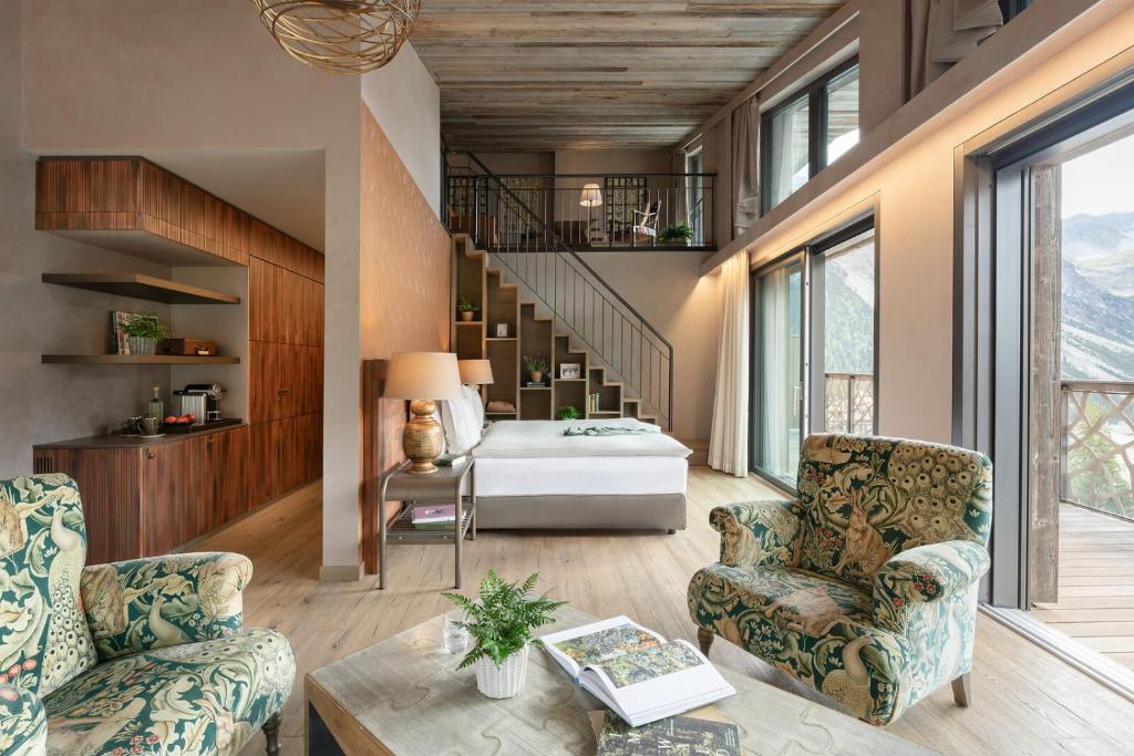 a living room with two chairs and a bed at Valsana Hotel Arosa - Small Luxury Hotel in Arosa