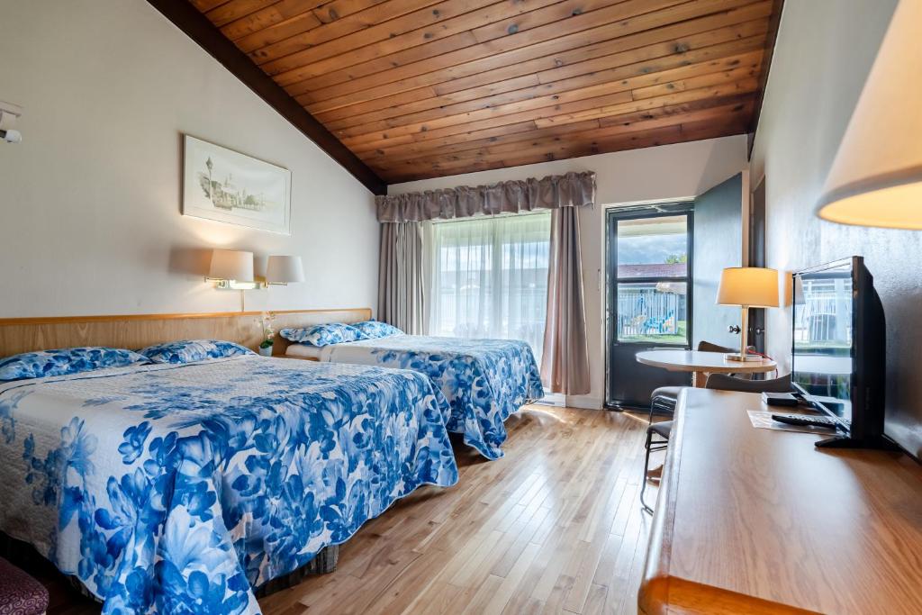 a hotel room with two beds and a table at Hotel Motel Bonsoir in Granby