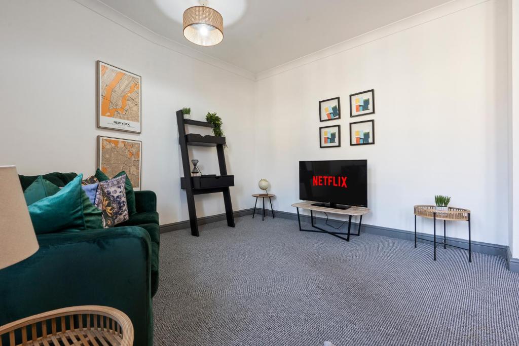 a living room with a green couch and a tv at Mariah Flat - 2 Bedroom getaway in Pontypool in Pontypool