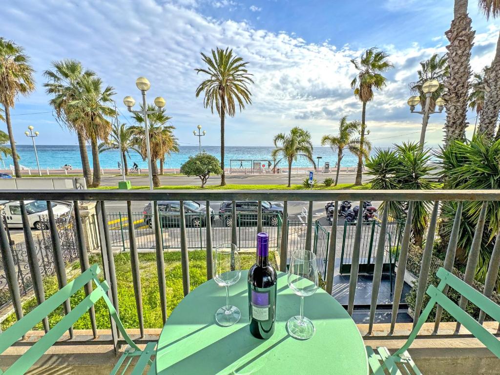 a bottle of wine on a table on a balcony overlooking the beach at Cosy Cariatides Condo Promenade in Nice