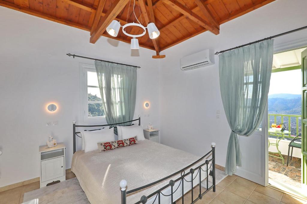 Un dormitorio con una cama y una ventana grande. en Skopelos villa Konstans, en Skopelos Town