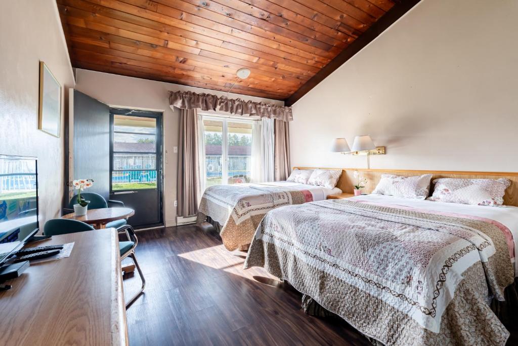 a hotel room with two beds and a television at Hotel Motel Bonsoir in Granby