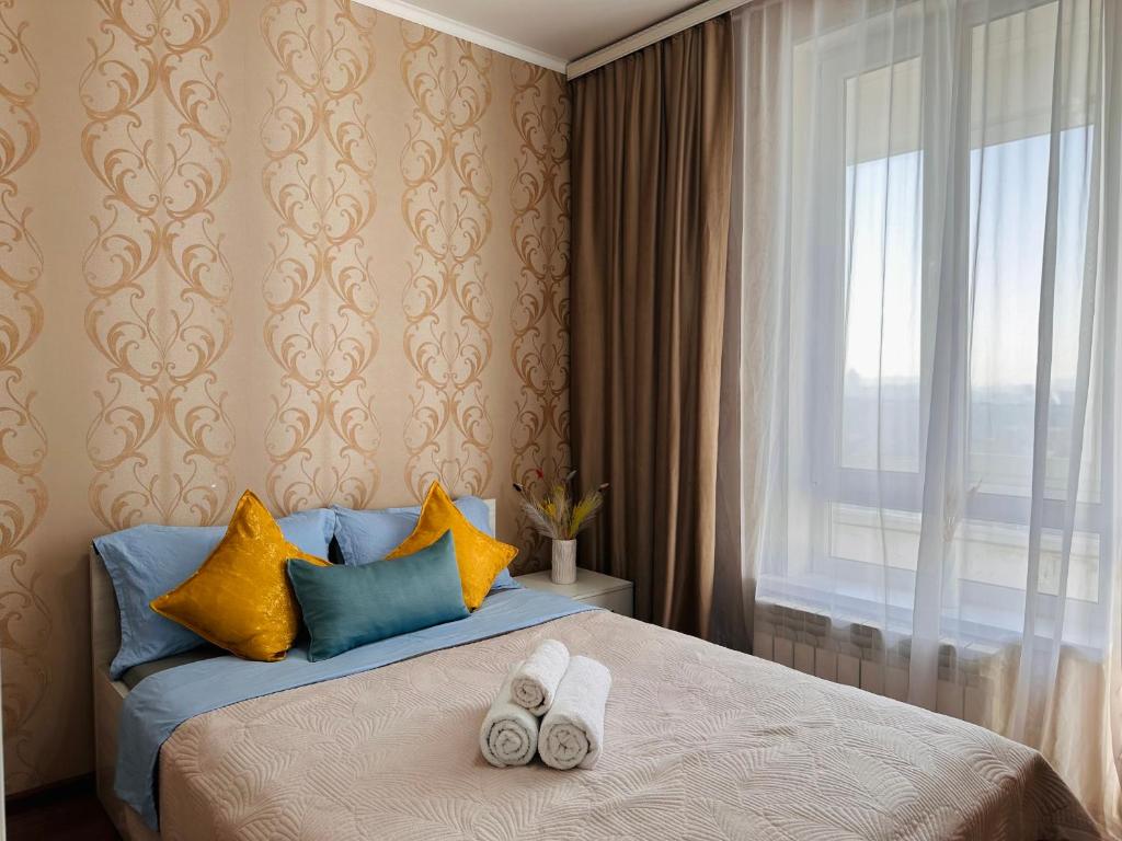 ein Schlafzimmer mit einem Bett mit zwei Handtüchern darauf in der Unterkunft Солнечная квартира на высоком этаже in Almaty