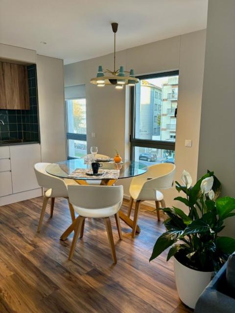 a dining room with a glass table and chairs at Three Little Birds in Guimarães