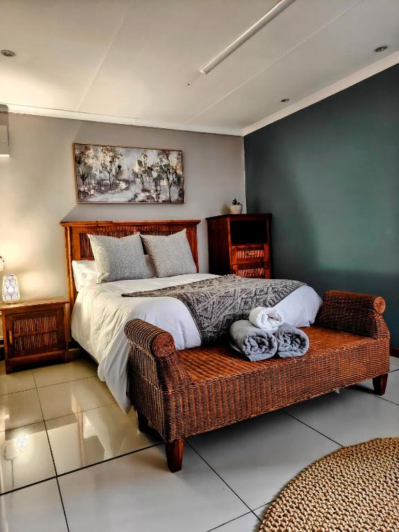 a bedroom with a bed and a wicker couch at Harrismith Country Cottage in Harrismith