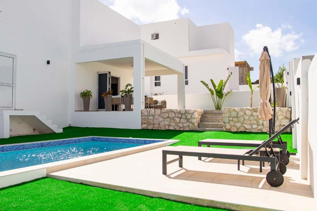 a white house with a swimming pool and green grass at 3 bedroom luxury vacation villa for a relaxed intimate feeling in Willemstad