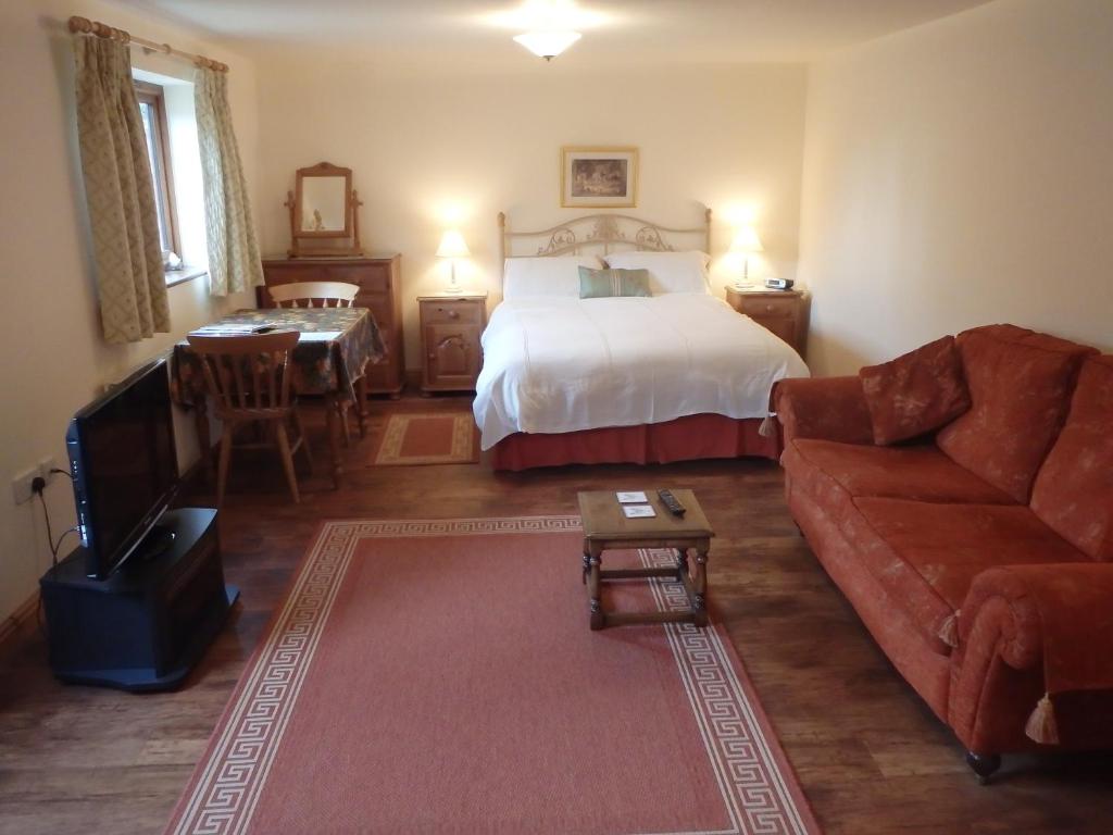 a bedroom with a bed and a couch and a table at The Courtyard, Laurel Farm in Lowestoft