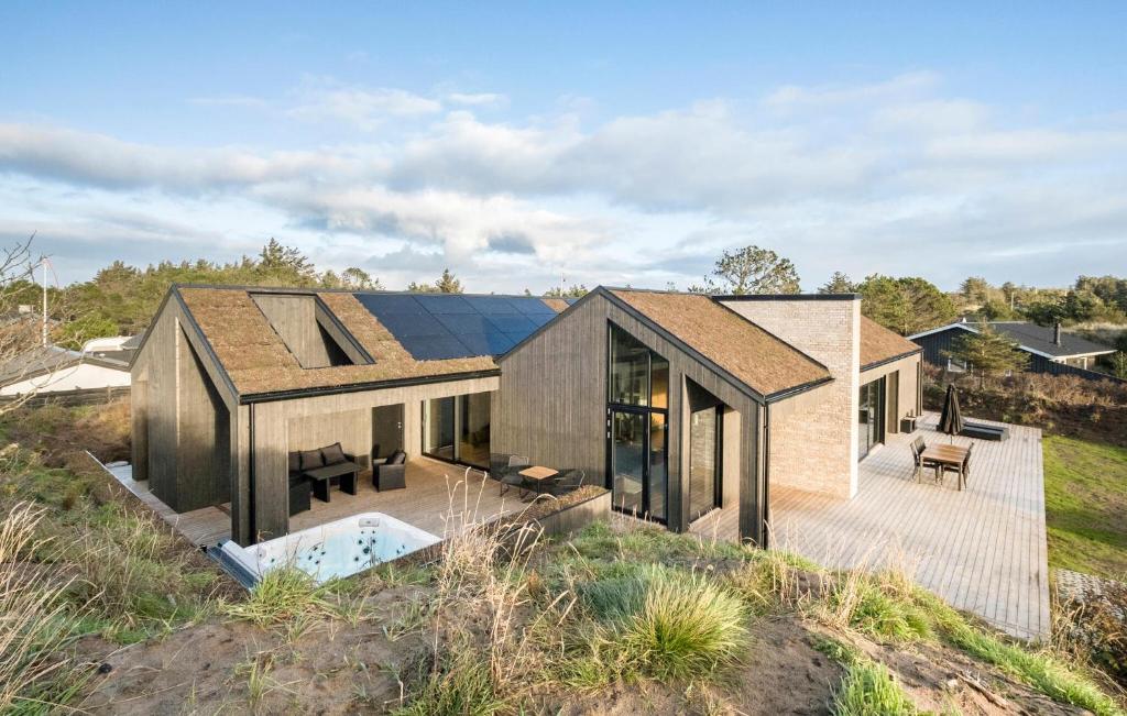 a house on top of a hill with a deck at 4 Bedroom Pet Friendly Home In Blokhus in Blokhus