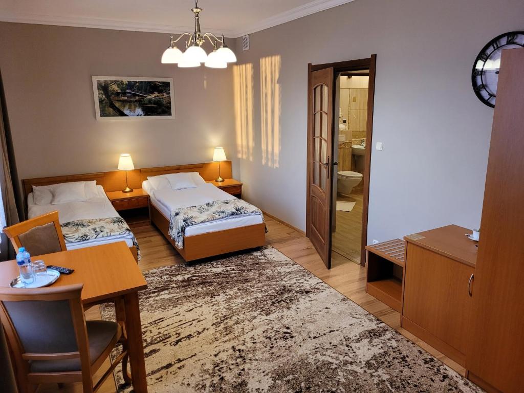 a hotel room with two beds and a table and a bathroom at Hotel Olimp in Chojnice