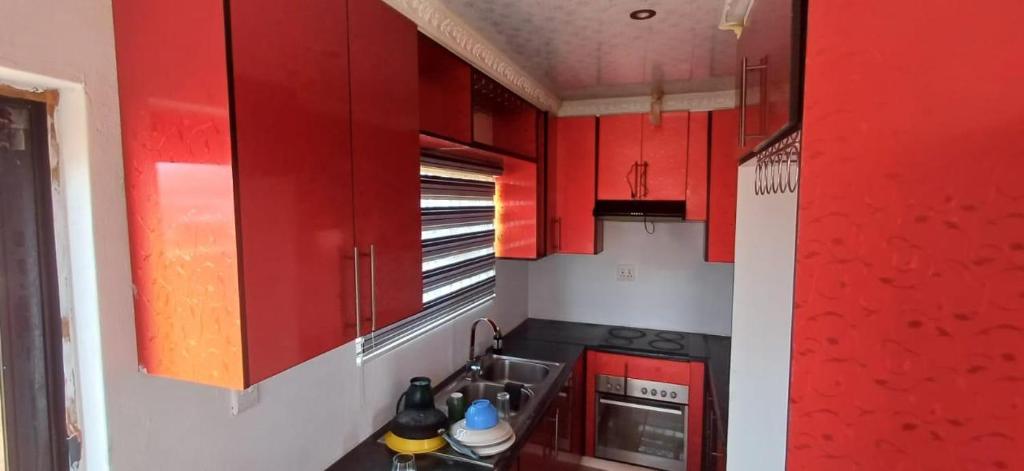 una piccola cucina con armadi rossi e lavandino di Siba's Place a Ga-Rankuwa
