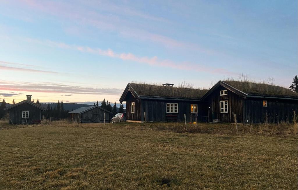 a black house in a field next to a field at Cozy Home In Fåvang With Wifi in Favang