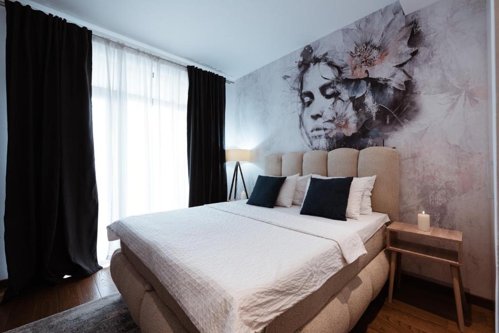a bedroom with a large bed and a painting on the wall at inJoy in Belgrade