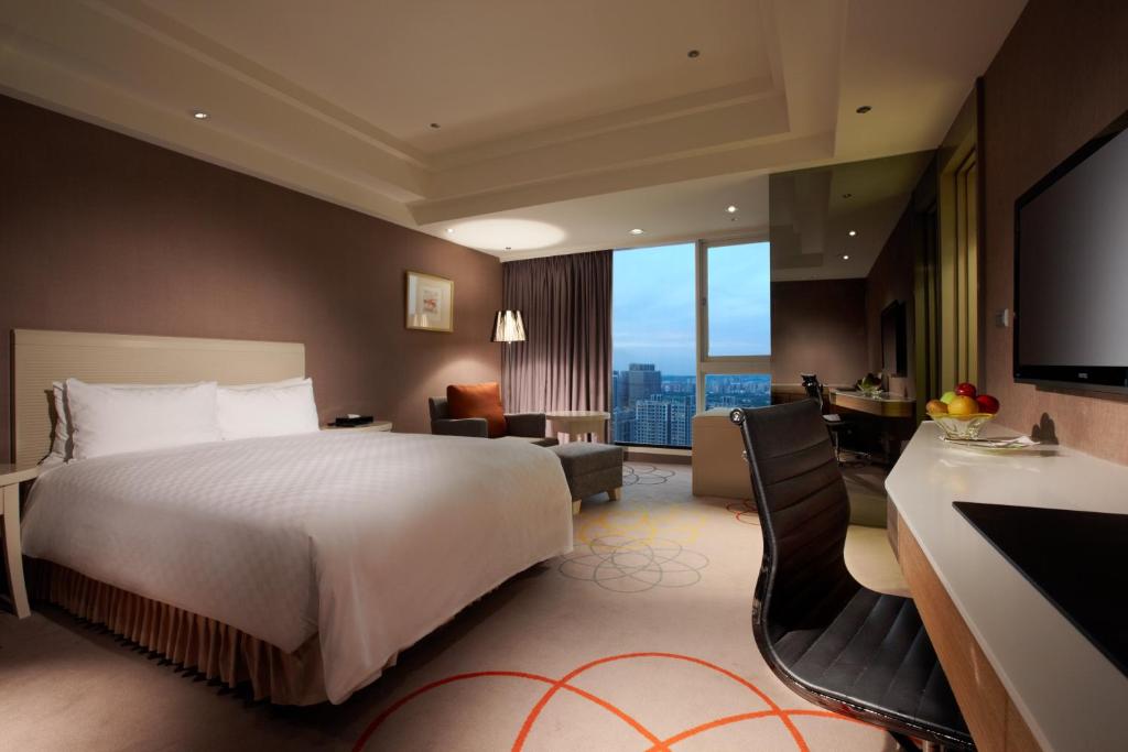 a hotel room with a bed and a desk with a television at Hotel Royal Hsinchu in Hsinchu City