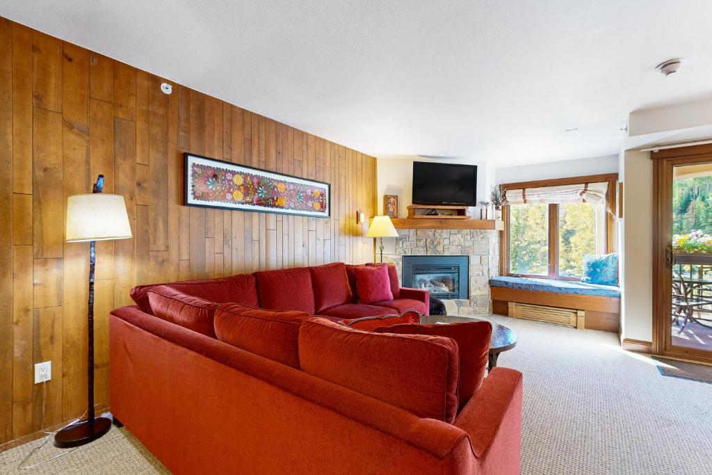 a living room with a red couch and a fireplace at Lion Square Lodge North 284 in Vail