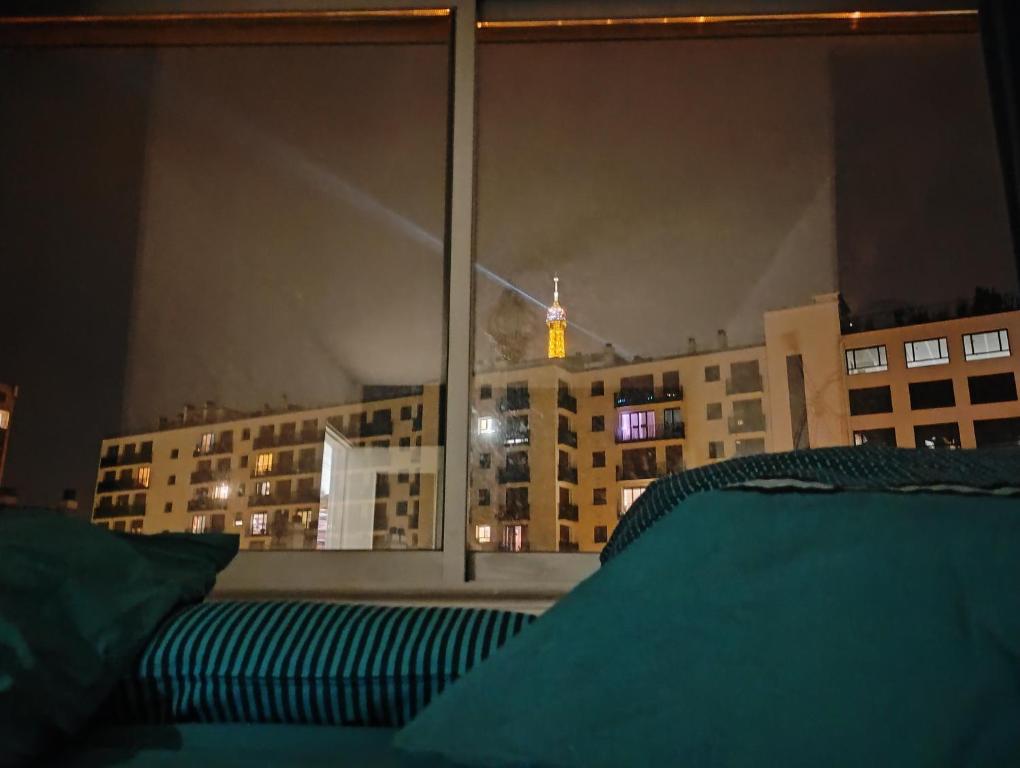 a bedroom with a view of a city at night at Eiffel Tower spacious 2-bedroom, 2-bathroom quiet apartment, elegant and peaceful in Paris