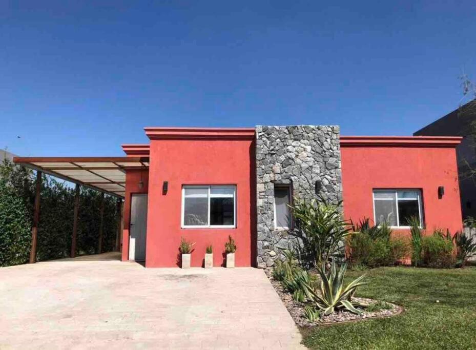 ein rotes Haus mit Stein und Rot in der Unterkunft Excelente casa en Barrio Privado Los Arces in Pilar