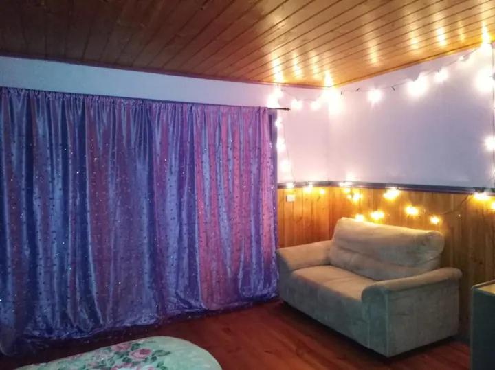 a living room with a couch and curtains with lights at Cheerful Bush House in Hepburn Springs