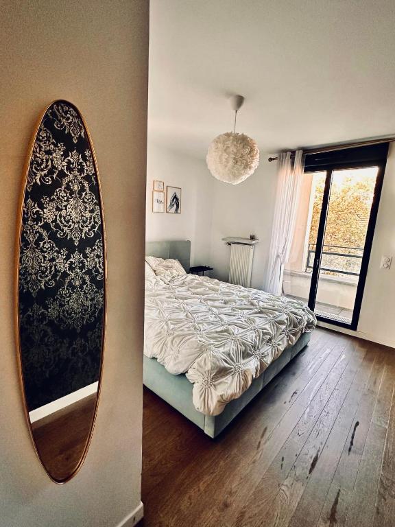 une chambre avec un lit et un miroir au mur dans l'établissement La Colombe, à Colombes