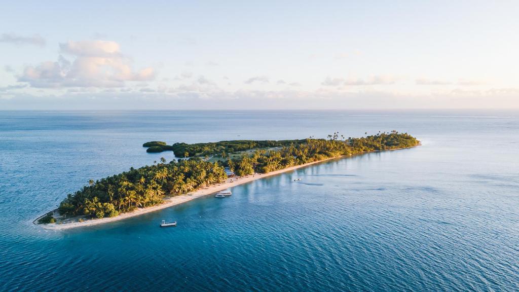 an island in the ocean with boats in the water at Likuri Island Resort Fiji in Natadola