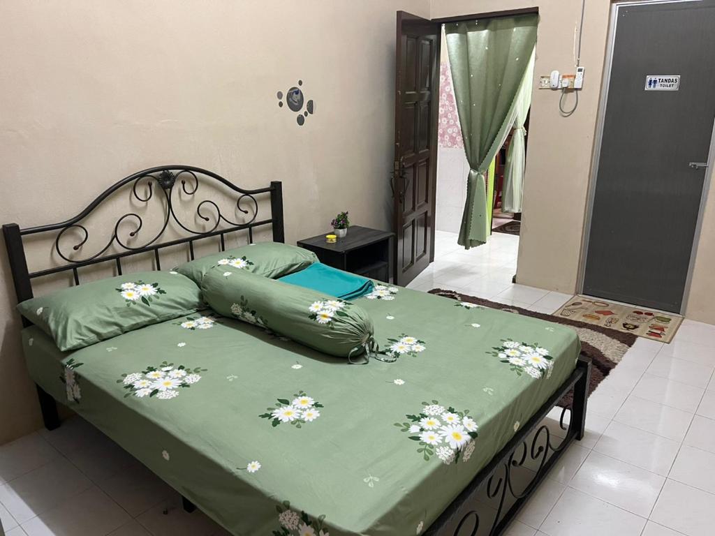 a bed with a green comforter with flowers on it at Homestay cikgu siti teluk intan in Teluk Intan