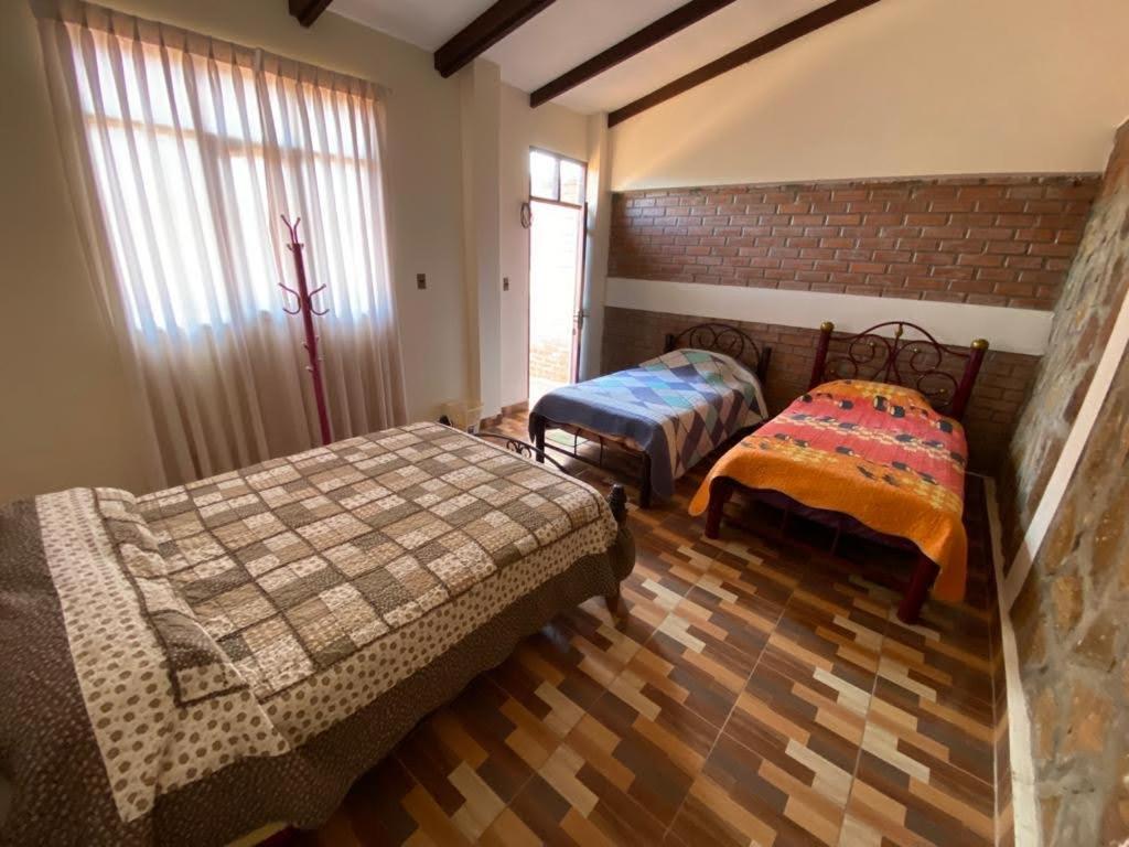 ein Schlafzimmer mit zwei Betten und einer Ziegelwand in der Unterkunft Hostal La Familia in Torotoro