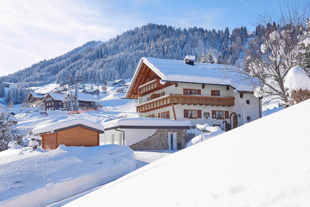 a house is covered in snow in a mountain at Ferienwohnungen Hörmann in Hirschegg