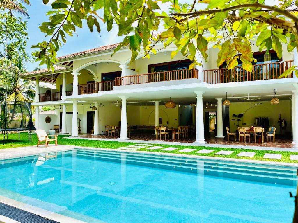 a villa with a swimming pool in front of a house at Charleston's Ahangama in Ahangama