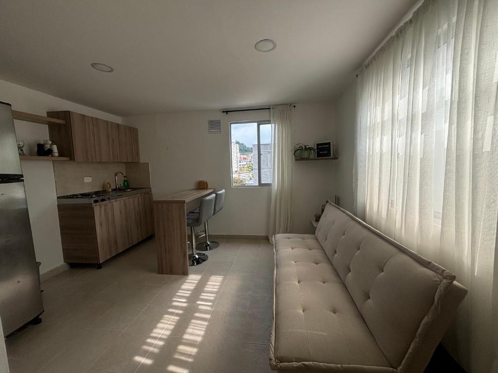 a living room with a couch and a kitchen at Apartamento acogedor cerca al Cable in Manizales