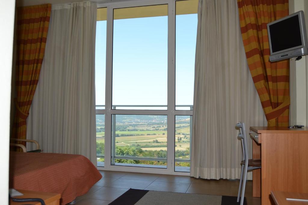 Albergo Umbria في Otricoli: غرفة بها نافذة كبيرة بها سرير وتلفزيون