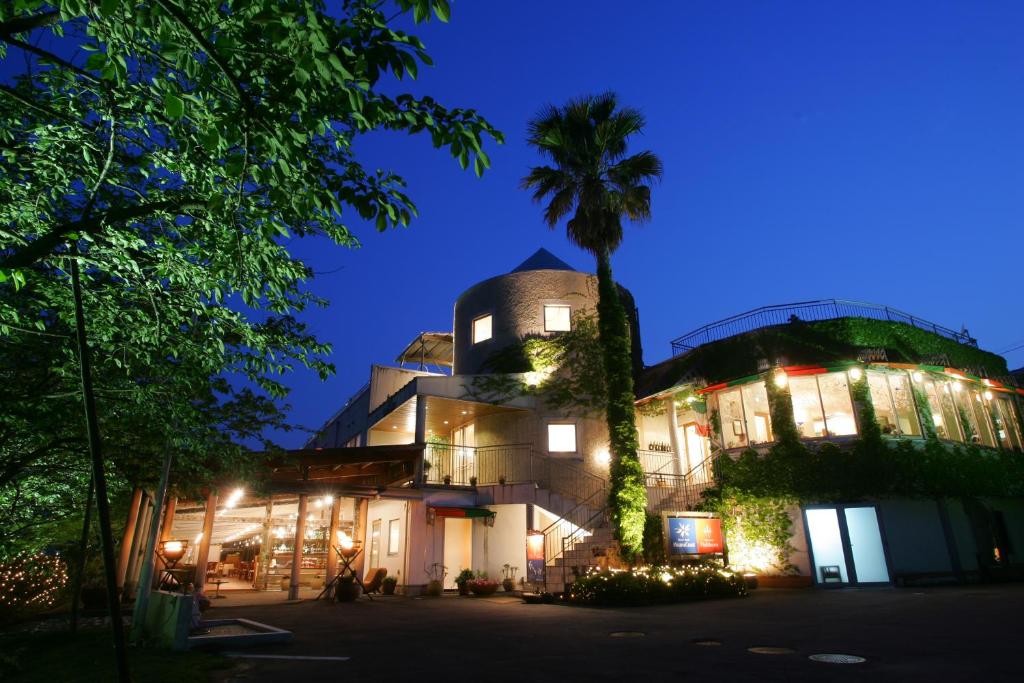 un bâtiment avec un palmier devant lui la nuit dans l'établissement Resort Hotel Moana Coast, à Naruto
