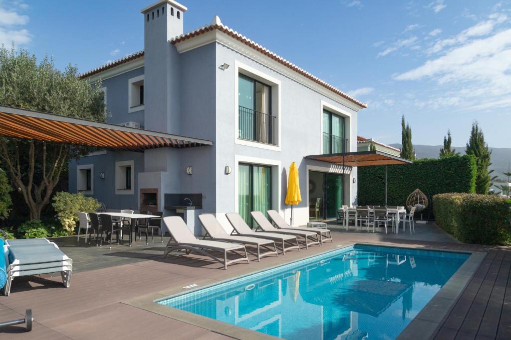 ein Haus mit einem Pool mit Stühlen und einem Tisch in der Unterkunft Villa Eden Sky in Prazeres in Prazeres