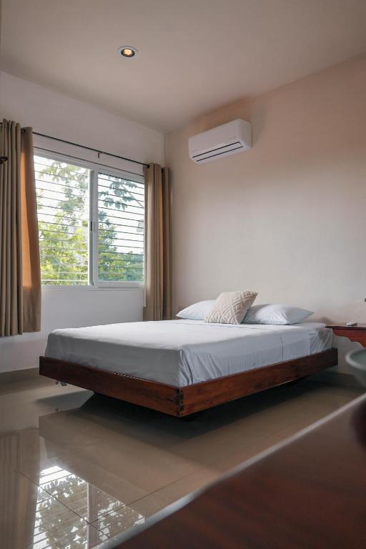 a bed in a bedroom with a large window at Apartamento 22 in Bacalar