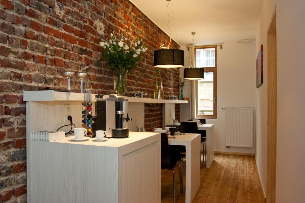 uma cozinha com balcões brancos e uma parede de tijolos em @Cocoon em Ypres