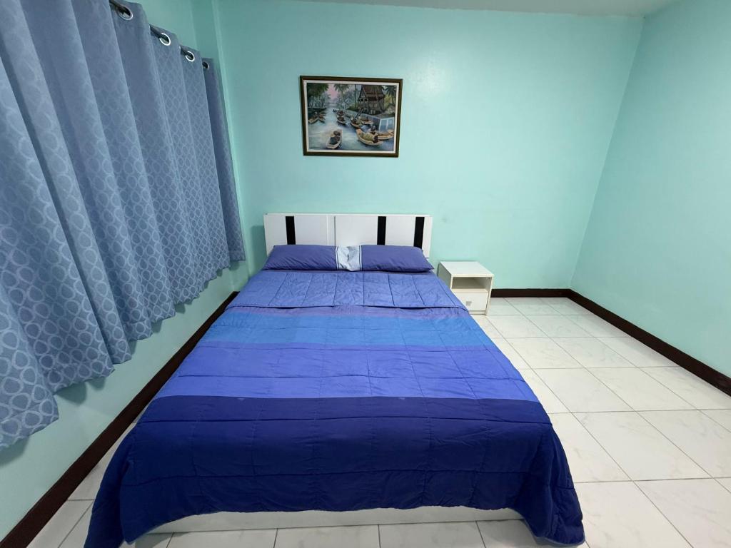 a blue bedroom with a bed with a purple comforter at Best Rent a Room in Nai Yang Beach