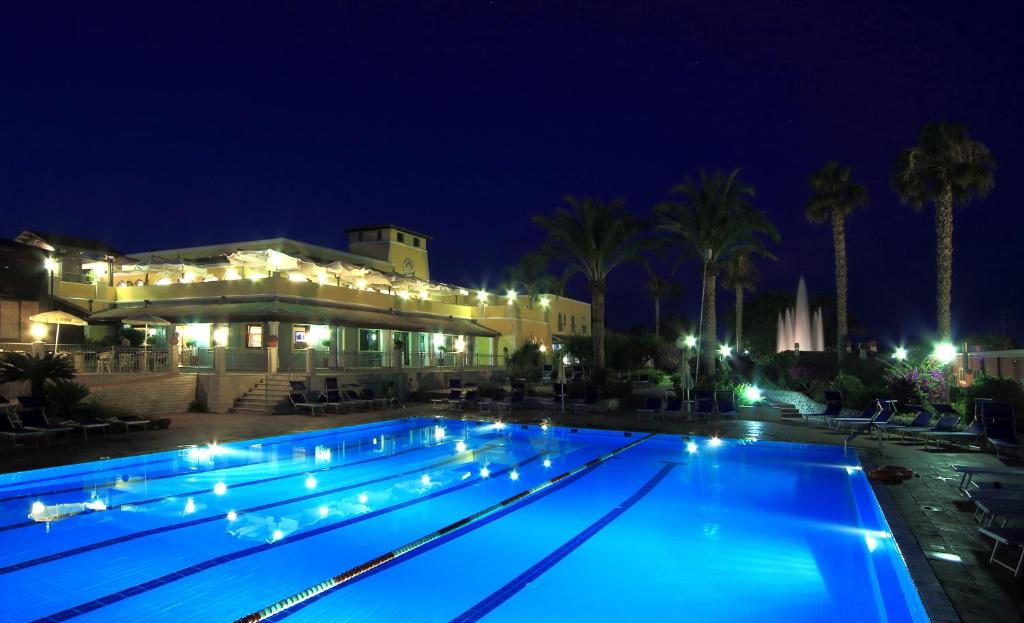 una piscina por la noche con luces. en iGV Club Baia Samuele, en Sampieri