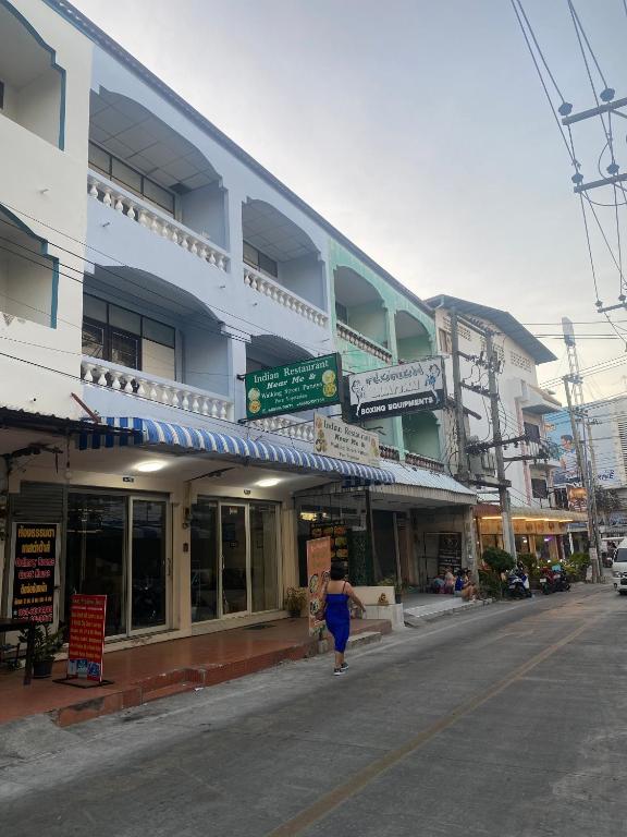 a woman walking down a street in front of a building at Walking Street Pattaya Beach Ordinary Rooms Guest House วอล์คกิ้งสตรีทพัทยาชายหาดพัทยาห้องธรรมดาเกสท์เฮ้าส์ in Pattaya Central