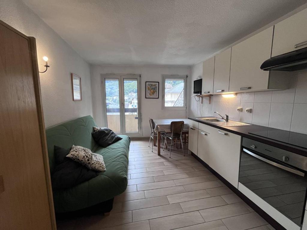 un salon avec un canapé vert et une cuisine dans l'établissement Studio cosy en centre-ville avec balcon et cellier à skis - FR-1-812-15, à Cauterets