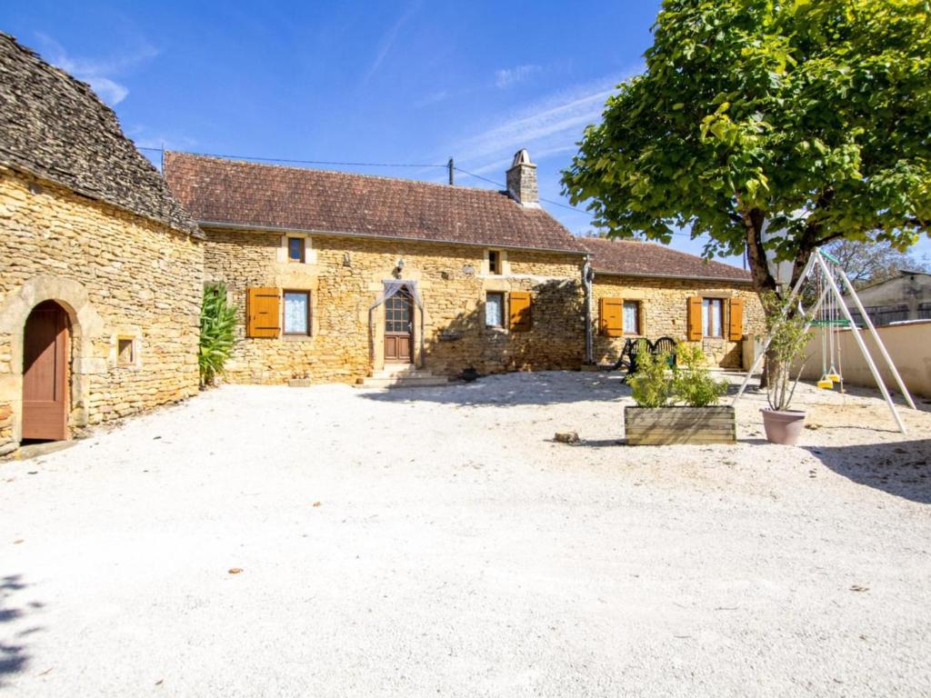 Charmante maison rustique en pierres, proche de Sarlat - FR-1-616-385 في Marcillac-Saint-Quentin: مبنى من الطوب القديم وامامه شجرة